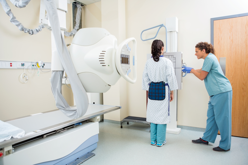 Eine Frau während einer Röntgen-Untersuchung trägt eine Bleischürze