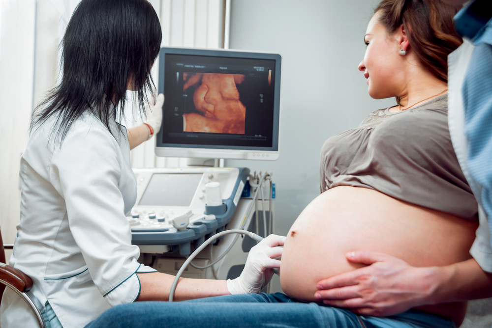 Schwangere Frau wird von Ärztin mit einem Ultraschallgerät untersucht