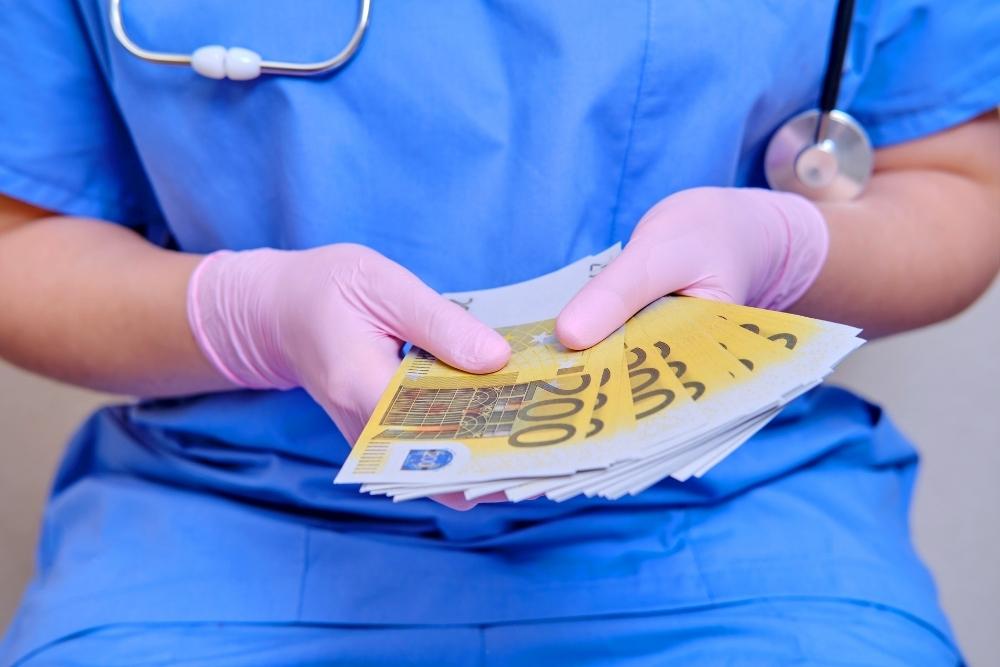 Arzt demonstriert sein Gehalt Geldscheine in der Hand