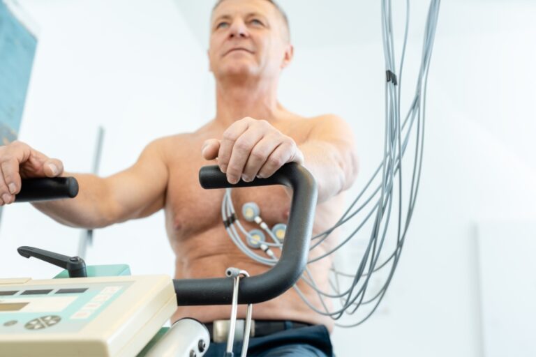 Patient sitzt während Belastungs-EKG (Ergometrie) auf einem Fahrradergometer.