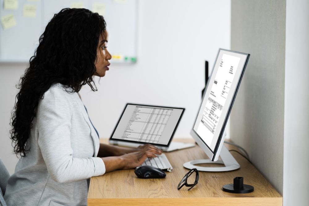 Ärztin sitzt vor Ihrem PC und arbeitet mit Praxissoftware