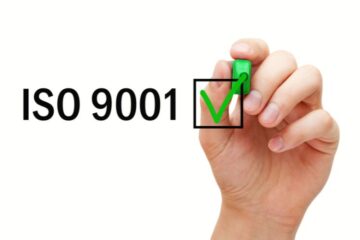 Hand setzt Checkliste-Häkchen neben ISO 9001, Symbol für Qualitätsmanagement in der Zahnarztpraxis