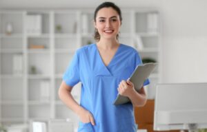 Hygienebeauftragte medizinische Fachangestellte (MFA) in blauer Kleidung mit Klemmbrett in moderner Arztpraxis
